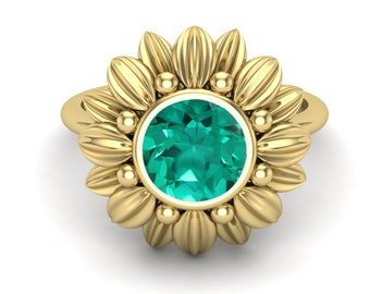 Puede incluir: Un anillo de oro con una piedra preciosa verde engastada en un diseño de girasol.