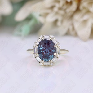 May include: A gold ring with a large oval-shaped blue gemstone surrounded by a halo of smaller diamonds. The ring is set on a white background.