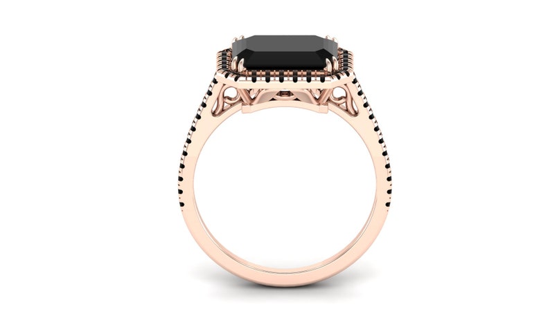 Op de afbeelding: Ros&eacute;gouden ring met een grote, rechthoekige zwarte edelsteen. De edelsteen is omgeven door een halo van kleinere zwarte stenen. De band is ros&eacute;goudkleurig, met zwarte stenen langs de zijkanten, wat een opvallend contrast cre&euml;ert.
