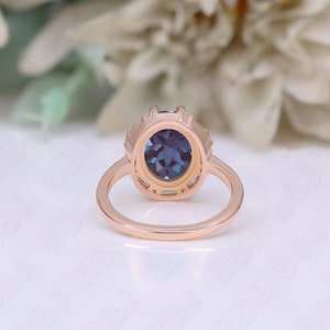 May include: A rose gold ring with a blue oval gemstone surrounded by smaller clear gemstones. The ring is set in a delicate, intricate design.
