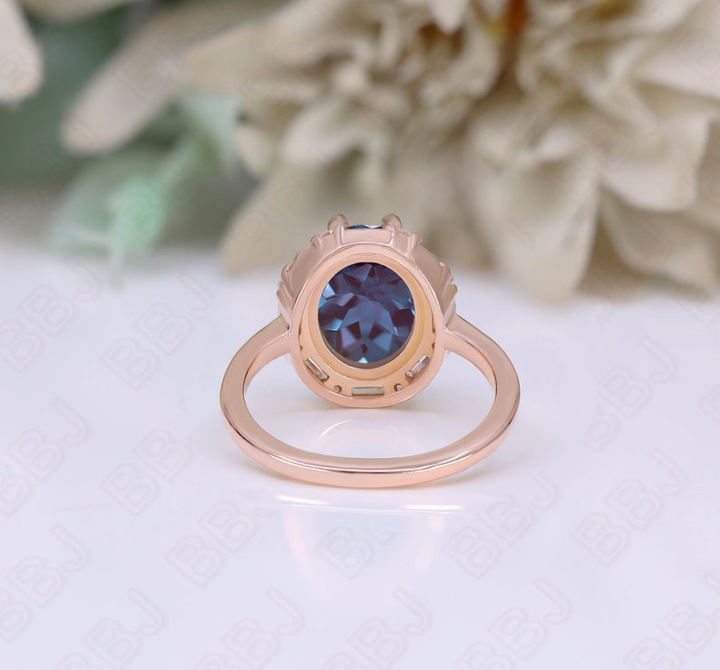 May include: A rose gold ring with a blue oval gemstone surrounded by smaller clear gemstones. The ring is set in a delicate, intricate design.