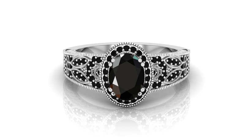 May include: A silver ring featuring an oval black gemstone encircled by smaller black gemstones. The ring boasts a delicate filigree design.