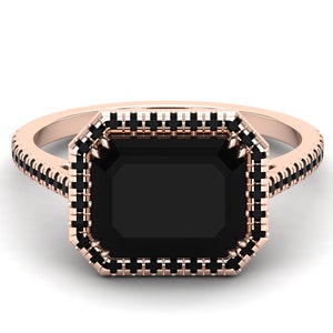 Op de afbeelding: Ros&eacute;gouden ring met een grote, rechthoekige zwarte edelsteen. De edelsteen is omgeven door een halo van kleinere zwarte stenen, met extra zwarte stenen langs de band. De ring heeft een klassiek, elegant ontwerp.