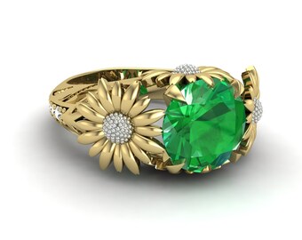 Puede incluir: Un anillo de oro con una gran piedra preciosa verde rodeada de dos engastes de oro en forma de margarita con piedras preciosas blancas en el centro.