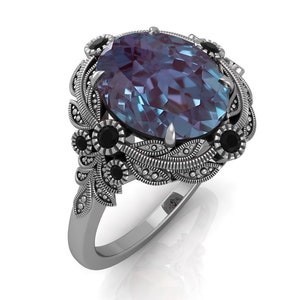 Puede incluir: Anillo de plata con una gema ovalada en tonos azules y morados. El anillo presenta detalles de filigrana floral y de hojas, acentuados con gemas negras. Un dise&ntilde;o cl&aacute;sico y elegante, ideal para ocasiones especiales.
