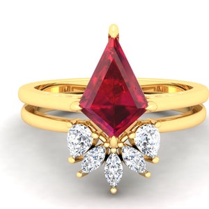 Op de afbeelding: Een gouden ring met een grote, rode, vlieger-vormige edelsteen omringd door kleinere, heldere, peervormige edelstenen.