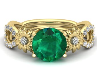 Puede incluir: Un anillo de oro con una gran piedra de esmeralda rodeada de dos delicados diseños de girasoles con detalles de diamantes.