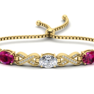 May include: A gold bracelet with a braided design and three oval-shaped gemstones. The center stone is white and the two outer stones are pink.