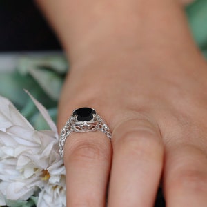 May include: A silver ring with a black gemstone set in a delicate filigree design.
