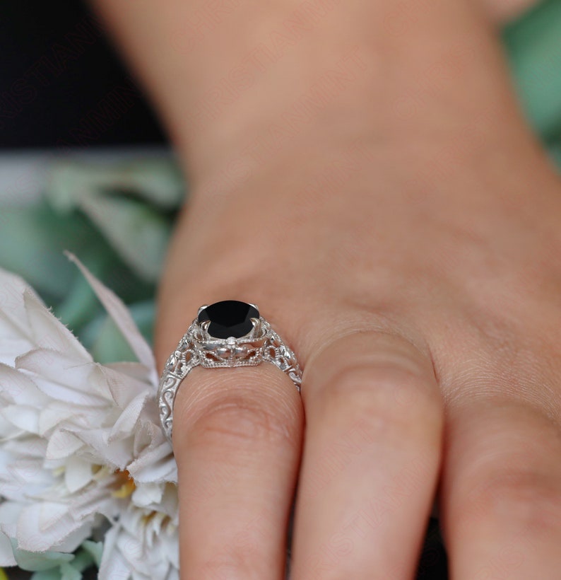 May include: A silver ring with a black gemstone set in a delicate filigree design.