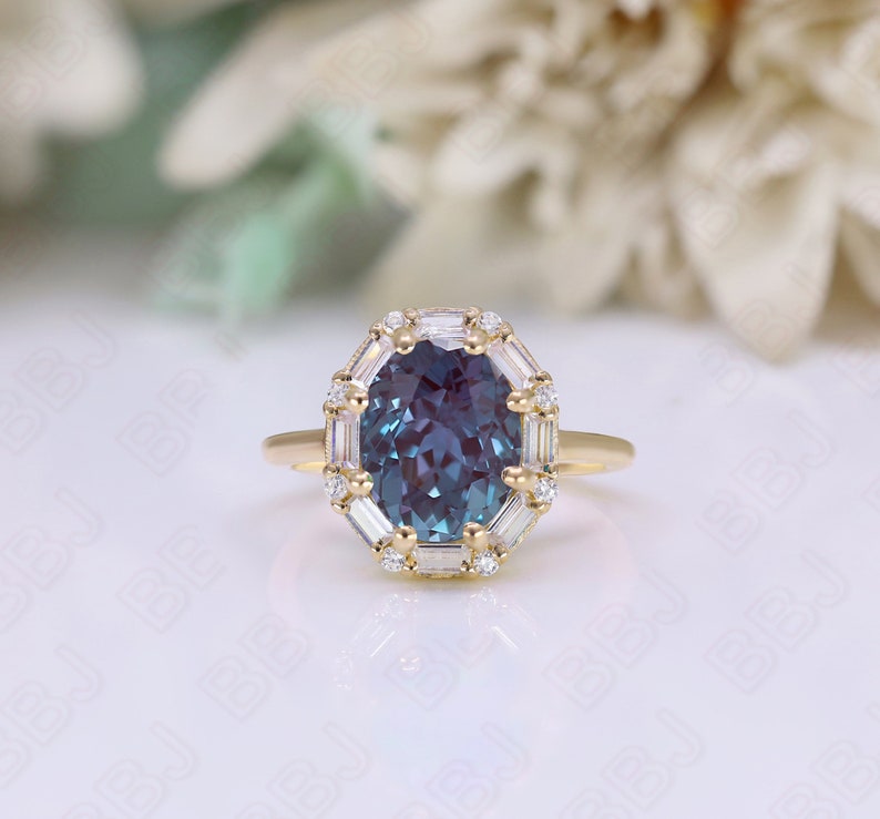 May include: A gold ring with a large oval-shaped blue gemstone surrounded by a halo of smaller diamonds. The ring has a delicate band.