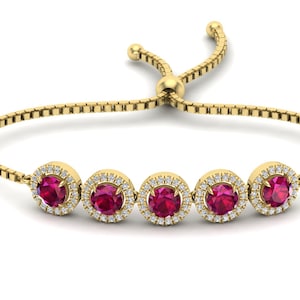 Puede incluir: Un brazalete de oro con un diseño de cadena y cinco piedras preciosas redondas rojas rodeadas de piedras preciosas blancas más pequeñas.
