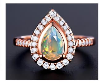 May include: A pear-shaped opal ring set in rose gold with a halo of smaller diamonds. The ring has a delicate, twisted band.
