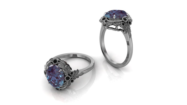 Puede incluir: Dos anillos de plata con un dise&ntilde;o floral ornamentado. Cada anillo presenta una gran piedra preciosa ovalada de color azul-p&uacute;rpura, rodeada de piedras negras m&aacute;s peque&ntilde;as y hojas de plata detalladas. Los anillos se muestran sobre un fondo blanco.