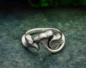 May include: A silver ring with a mushroom design. The ring is made of two mushrooms that are intertwined.