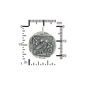 May include: Silver pendant charm featuring an owl with a crescent moon and olive branch, with the inscription "A&Theta;E". The pendant is approximately 2 cm in diameter.