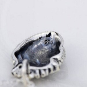 May include: Silver pendant with a detailed design and the inscription "S925" on the back.