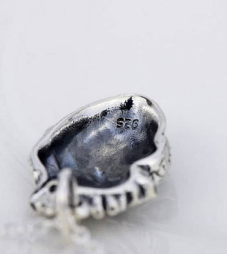 May include: Silver pendant with a detailed design and the inscription "S925" on the back.