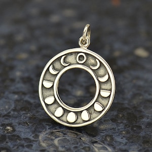 May include: Silver pendant featuring a circle with eight phases of the moon, including a full moon, crescent moon, and new moon.