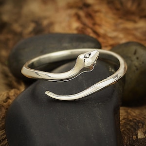 May include: A silver-toned metal ring shaped like a coiled snake. The band features a smooth, polished finish with a detailed head at one end and a tapered tail at the other, forming an open, adjustable design that wraps around the finger.