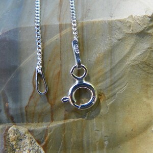 May include: A silver chain necklace with a lobster clasp closure. The clasp is marked with the number "925", indicating that the necklace is made of sterling silver.