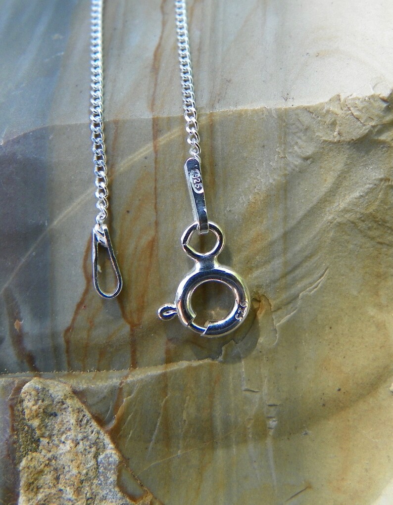 May include: A silver chain necklace with a lobster clasp closure. The clasp is marked with the number "925", indicating that the necklace is made of sterling silver.