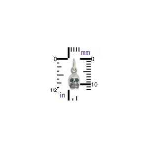 May include: A silver skull charm with a black face, measuring approximately 10 mm in diameter. The charm is shown against a white background with a ruler for size reference.