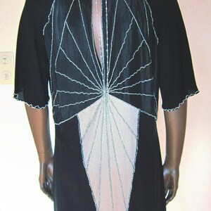 Pode incluir: Um vestido preto com um design geom&eacute;trico que apresenta um padr&atilde;o branco e bege. O vestido tem costas baixas e uma bainha festonada.