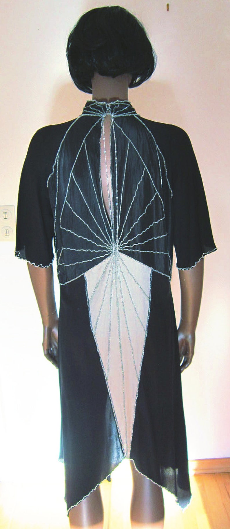 Pode incluir: Um vestido preto com um design geom&eacute;trico que apresenta um padr&atilde;o branco e bege. O vestido tem costas baixas e uma bainha festonada.