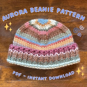 Peut inclure: Un bonnet tricoté multicolore avec un bord côtelé. Le chapeau présente des rayures dans les tons de rose, de bleu et de marron. Le texte sur l'image indique "AURORA BEANIE PATTERN" et "PDF - INSTANT DOWNLOAD".