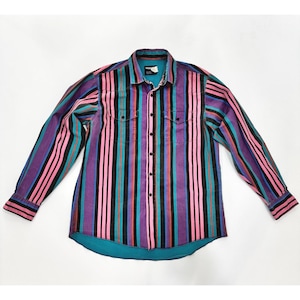 May include: A long-sleeved button-down shirt with vertical stripes in pink, black, teal, purple, and orange. The shirt has two chest pockets and a turquoise lining at the collar and hem. The Wrangler brand label is visible.