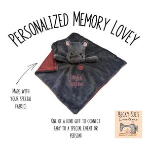 May include: A personalized memory lovey with a gray hippo plush head and a gray and burgundy blanket. The name "Layla Jayne" is embroidered in pink. Text reads "Made with your special fabric!" and "One of a kind gift to connect baby to a special event or person!"