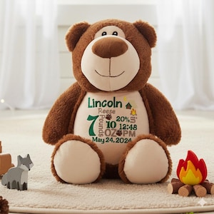 May include: A brown plush teddy bear with a cream-colored belly featuring embroidered text: Lincoln Reese, 7 Pounds 10 OZ, 20 inches, 12:48 PM, May 24, 2024, along with a small campfire and bear paw print graphics in green and brown thread.