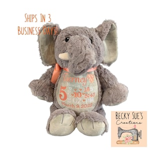 May include: A gray plush elephant toy with a peach-colored ribbon around its neck. The elephant's belly features embroidered text: Tierney, 5 Pounds 10 OZ, 18 inches, 8:43 PM, and March 9, 2022, in peach and gray thread colors.