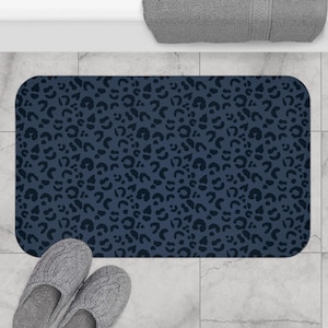 May include: A dark blue bath mat with a black leopard print pattern. The mat is made of a soft, absorbent material and is perfect for adding a touch of style to any bathroom.