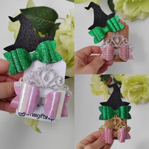 May include: A collection of glittery hair accessories, including a black witch hat, green bow, pink bow, and silver tiara. The accessories are displayed on white cards. The text "...nasgifts..." is visible on the cards.