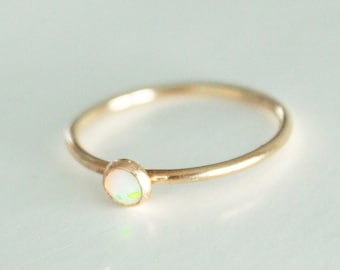 May include: A delicate gold ring with a small, white opal gemstone.