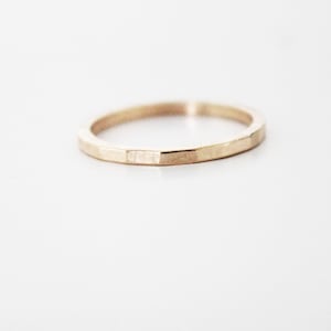 May include: A simple gold band ring with a hammered texture.