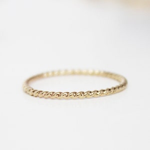 Puede incluir: Un fino anillo de oro con un diseño de cuerda trenzada.