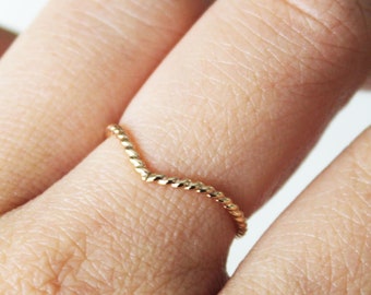May include: A gold-coloured ring with a twisted, v-shaped design.