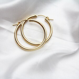 May include: A pair of gold hoop earrings. The earrings are thick and have a smooth finish.