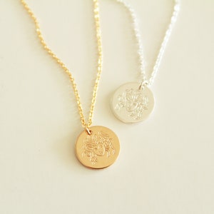 K&ouml;nnte beinhalten: Zwei Halsketten mit runden Anh&auml;ngern, die ein detailliertes, graviertes Bild eines Frauenkopfes zeigen. Eine Halskette hat eine goldene Kette und einen Anh&auml;nger, die andere eine silberne Kette und einen Anh&auml;nger.