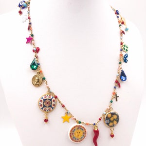 Peut inclure: Un collier à chaîne dorée orné de breloques colorées, notamment un œil bleu, un cristal vert en forme de goutte, une médaille religieuse dorée, une étoile jaune, un disque solaire en céramique, un piment rouge et un motif de citrons.
