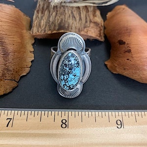 Puede incluir: Un anillo de plata con una piedra turquesa engastada en un diseño detallado. El anillo tiene un diámetro de aproximadamente 8 pulgadas.