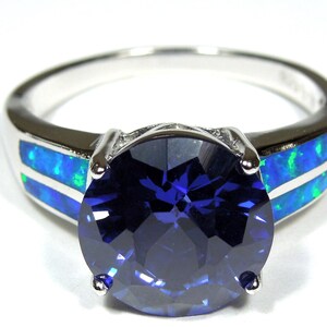 Pu&ograve; includere: Un anello d'argento con una grande pietra preziosa blu circondata da due bande di opale blu e verde.