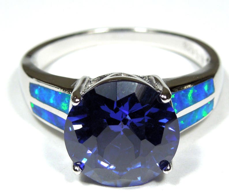 Pu&ograve; includere: Un anello d'argento con una grande pietra preziosa blu circondata da due bande di opale blu e verde.