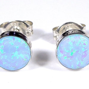 May include: A pair of silver stud earrings with round blue opal stones.