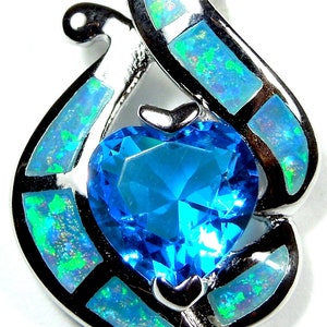 May include: A silver pendant with a blue heart-shaped gemstone surrounded by a swirl of white opal stones.