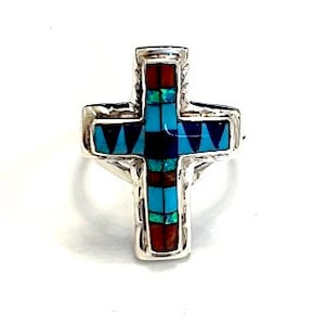 May include: Sterling silver ring with a cross design inlaid with turquoise, red coral, and lapis lazuli stones.