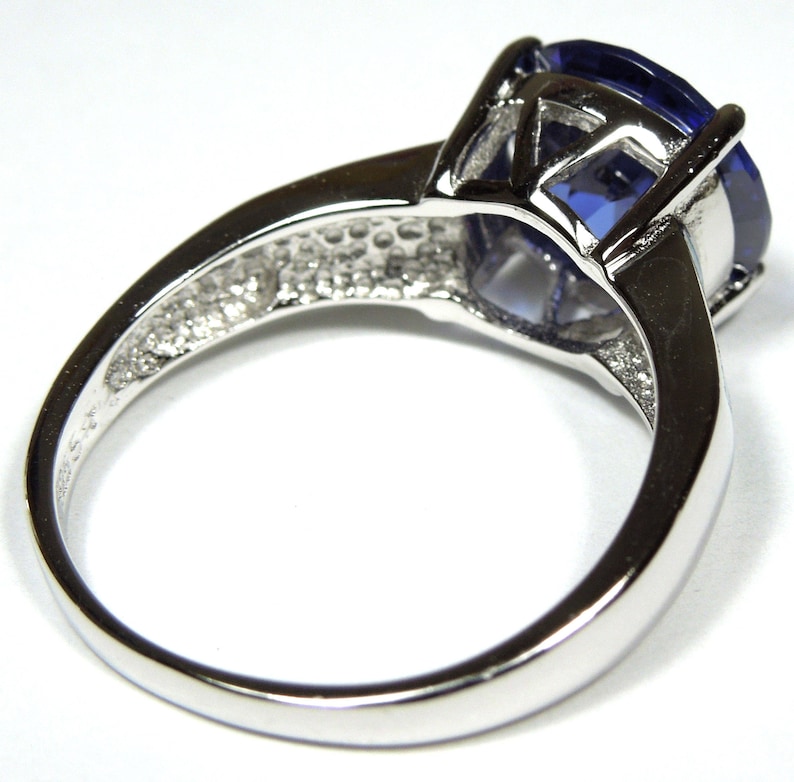 Pu&ograve; includere: Un anello d'argento con una grande pietra preziosa ovale di colore blu scuro. L'anello ha una fascia semplice e una montatura a griffe.